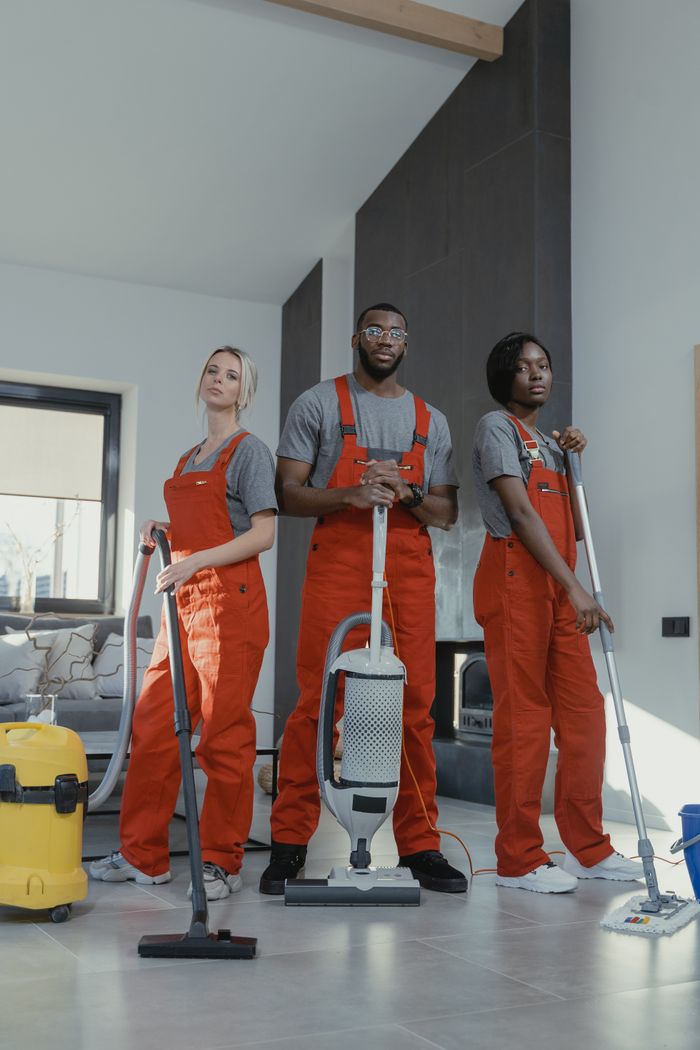 creative-01 Three cleaners in uniform with equipment in a modern home interior, showcasing teamwork and professionalism.