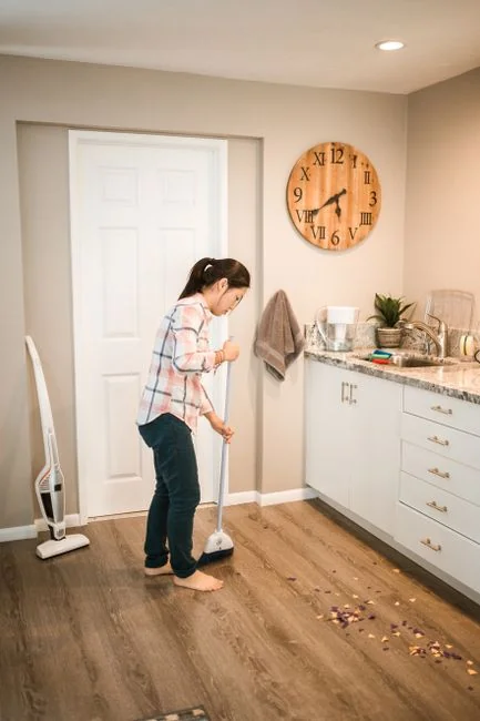 creative-03 Une femme adulte en combinaison rouge utilise un aspirateur dans un intérieur moderne, en mettant l’accent sur les tâches de nettoyage.